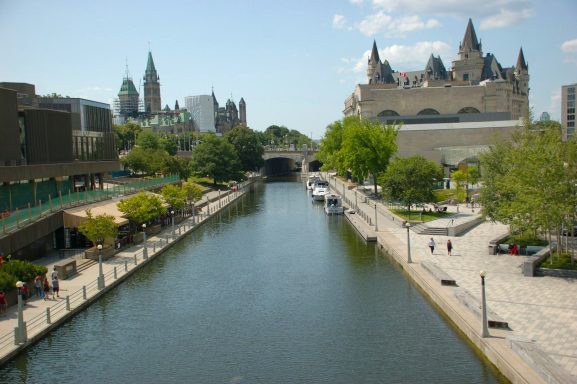 Scenic view of a canal bordered by greenery and buildings in a city landscape.