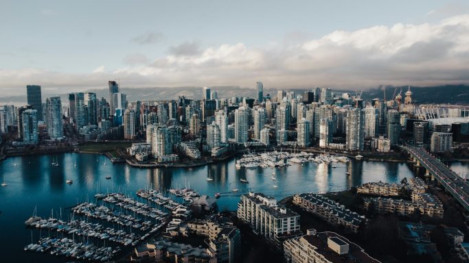 Aerial view of a modern city skyline with water and boats nearby.