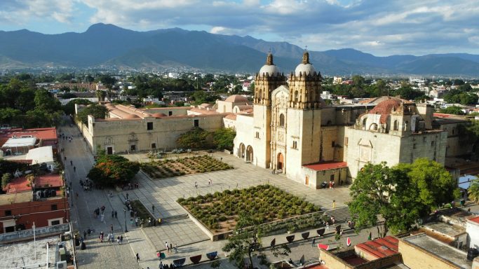 Oaxaca Aerial view of a historic church surrounded by a plaza and mountains in the background.