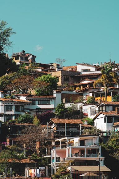 Valle de Bravo Colorful hillside houses surrounded by greenery under a clear blue sky.