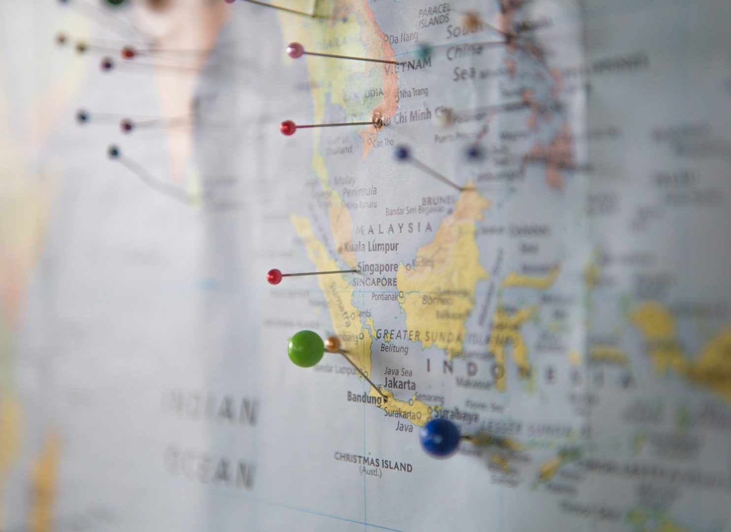 Colorful pins mark locations on a blurred geographical map.