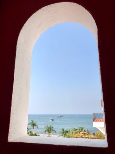 Ixtapa View of the ocean and palm trees through an arched window.
