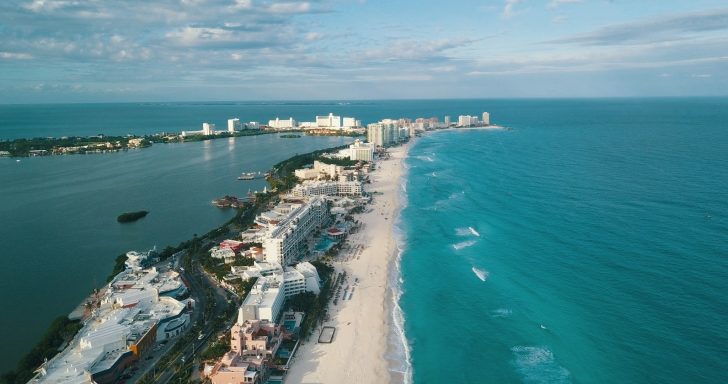 Cancun Aerial view of a coastline with sandy beach and turquoise water, along a city skyline.