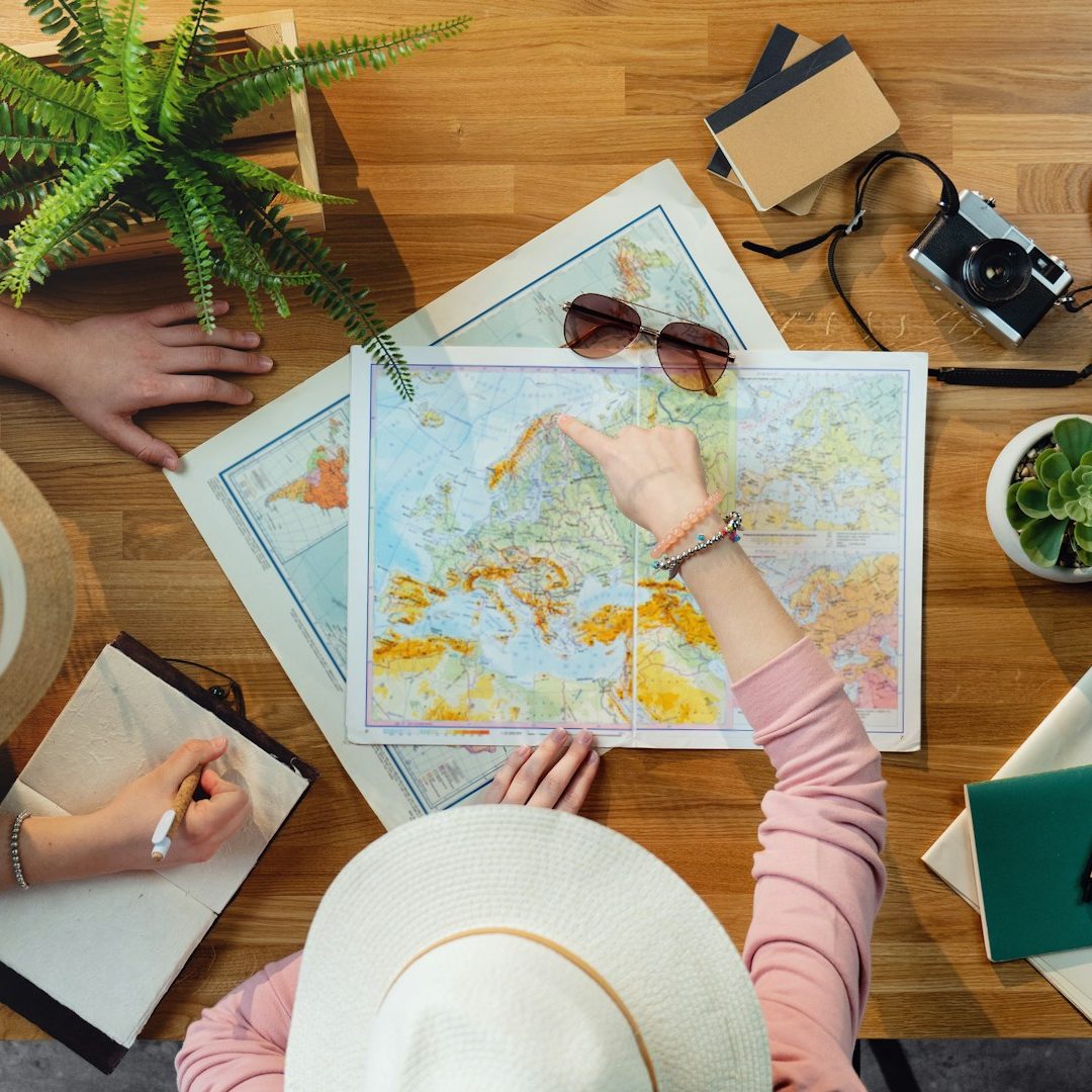 Aerial view of a map on a table with a camera, notebook, and potted plant.