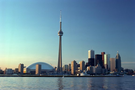 Toronto skyline featuring the CN Tower and Rogers Centre under a clear blue sky.